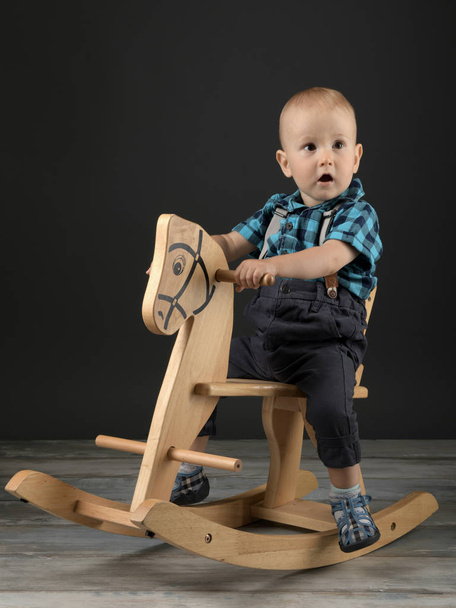 Sweet little boy playing at home with wooden horse, childhood games - Фото, зображення