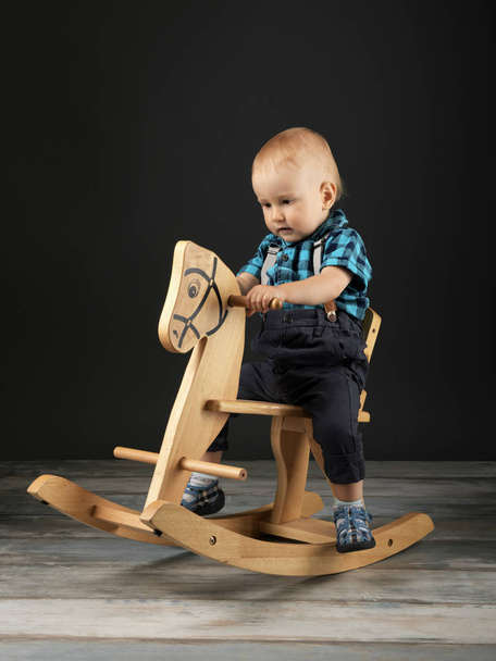 Sweet little boy playing at home with wooden horse, childhood games - Photo, Image