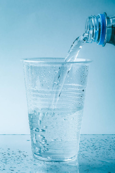 Чиста прісна вода вливається в скляну або пластикову чашку в краплі крупним планом, здоровий напій
 - Фото, зображення