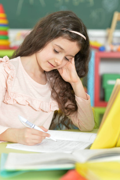 Cute schoolgirl doing homework in classroom  - Fotografie, Obrázek