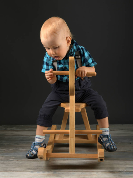 Sweet little boy playing at home with wooden horse, childhood games - Foto, immagini