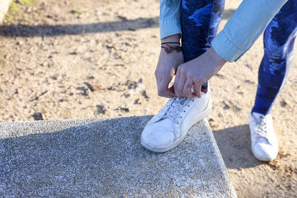 Woman tying the shoelaces on running track on a step - Valokuva, kuva