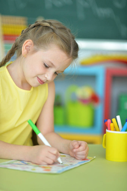  cute little girl drawing with felt pen while sitting at table in her room - Photo, Image