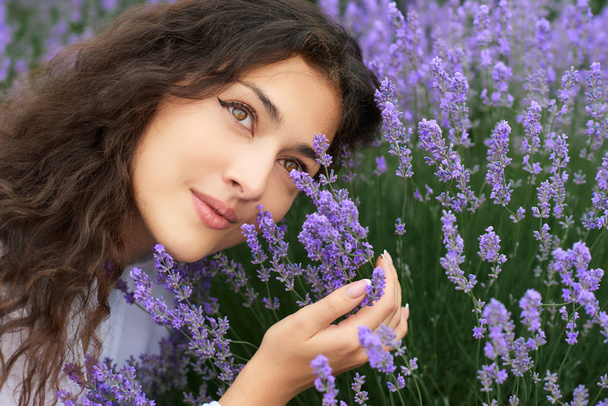 schöne junge Frau Porträt auf Lavendelblüten Hintergrund, Gesicht Nahaufnahme - Foto, Bild