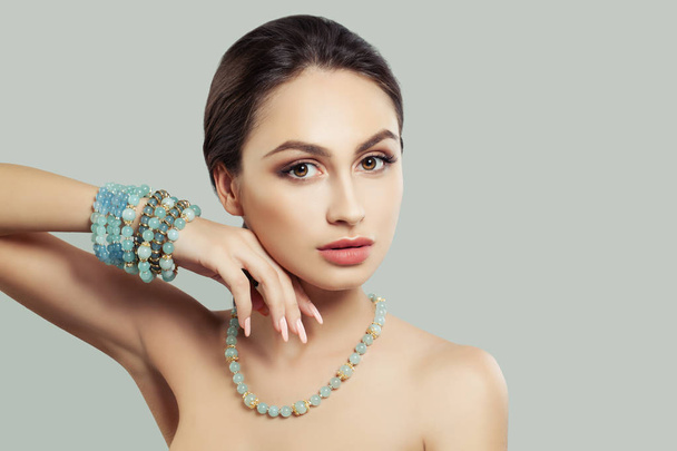 Ελκυστική νεαρή γυναίκα με το μακιγιάζ, κοσμήματα κολιέ και βραχιόλι σε φόντο με αντίγραφο χώρου - Φωτογραφία, εικόνα