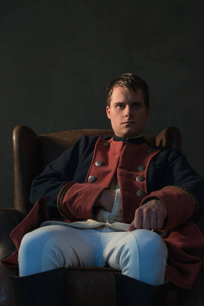 Regência histórica homem com mão na jaqueta sentado na cadeira
. - Foto, Imagem