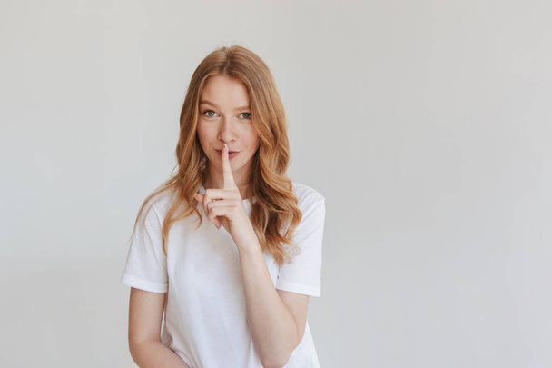 Image of young serious redhead woman isolated over white wall background showing silence gesture. - Foto, Bild