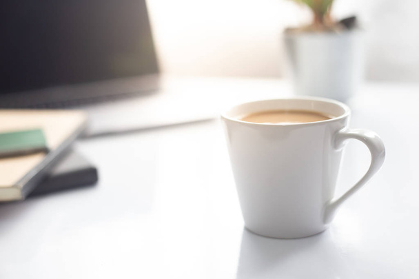 Tasse à café sur ordinateur portable sur table blanche au soleil du matin, Espace de travail - Photo, image