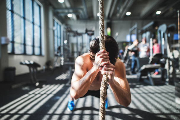 Fit young man in gym working out with climbing rope. - Foto, Imagem