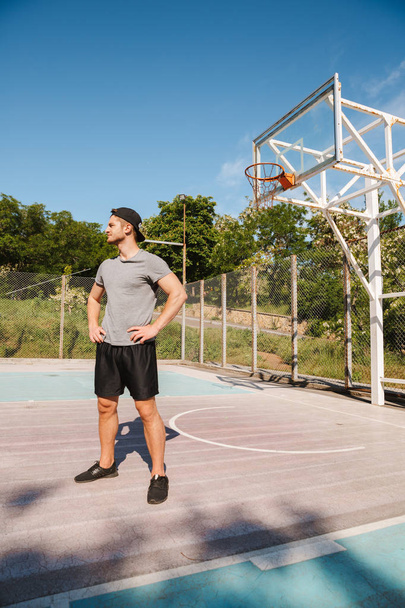 Confident young sportsman in shorts standing outdoors at the basketball court - Foto, Imagen