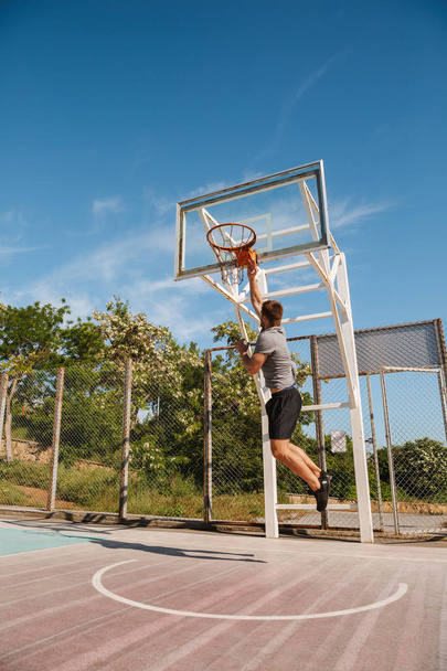 Young sportsman playing basketball on a court outside - Foto, afbeelding
