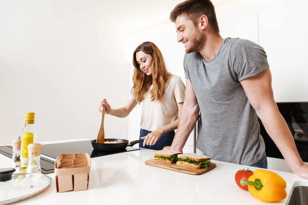 Smiling young couple cooking lunch together - Foto, imagen