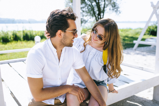 coppia seduta su una panchina di legno sulla spiaggia della città e guardarsi
 - Foto, immagini