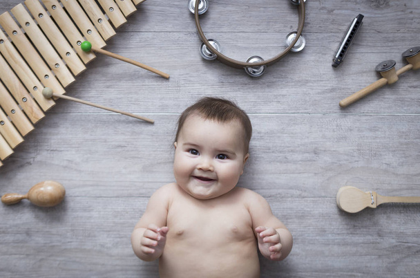 müzik aletleri ahşap gri zemin üzerinde çevrili güzel küçük bebek - Fotoğraf, Görsel