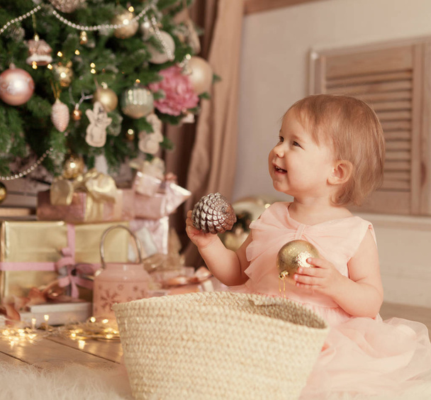 Portrait of funny happy child on christmas background. Small Girl playing with new year ball. - Фото, зображення