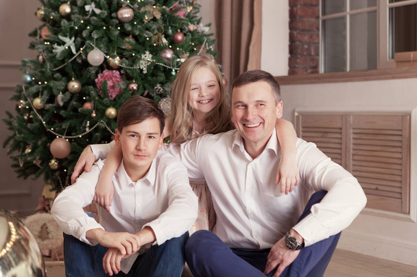 Portrait of beautiful happy family, merry father, daughter and son are sin Christmas decorations, indoor - Fotó, kép