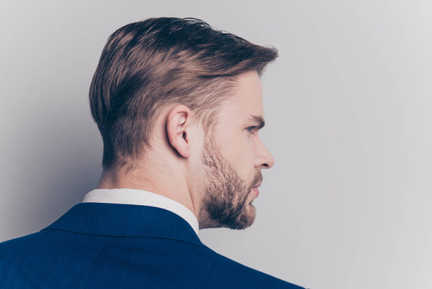Rear view, close up portrait of stunning, attractive, concentrated, modern man in blue suit, jacket, shirt with healthy hair, turned his head to the side, isolated on grey background - 写真・画像