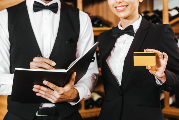 обрезанный снимок пары винных стюардов с ноутбуком и золотой кредиткой в винном магазине
 - Фото, изображение