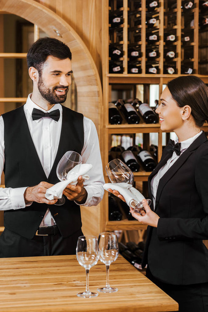 couple of wine stewards wiping glasses and chatting at wine store - 写真・画像