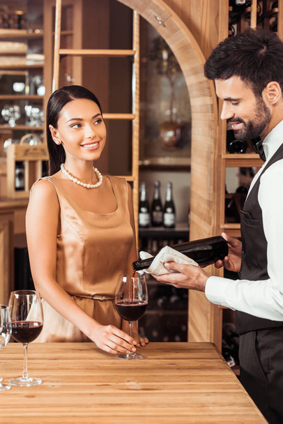 Weinverwalter schenkt Wein für junge attraktive Frau im Weinladen ein - Foto, Bild