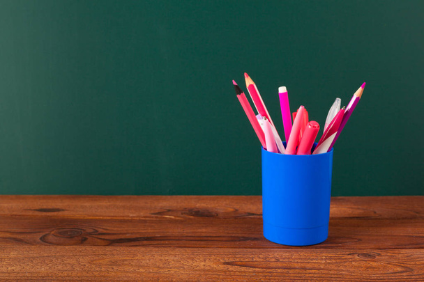 School supplies on a wooden table and blackboard background - Foto, imagen