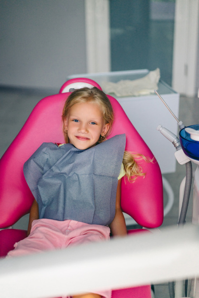 Porträt eines lächelnden Kindes, das in Zahnarztpraxis in die Kamera blickt - Foto, Bild