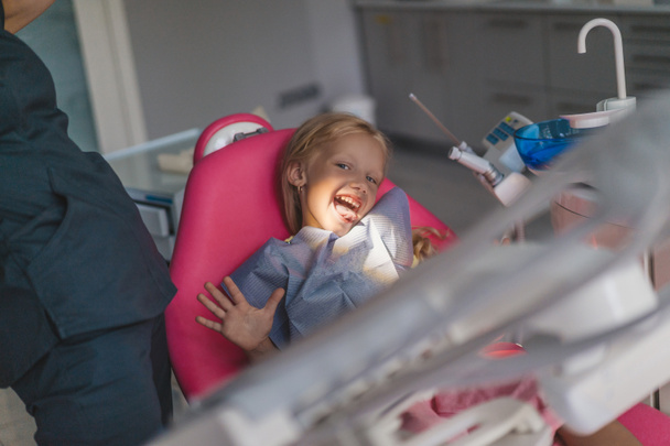 歯科医と歯科医のオフィスの椅子のうちの舌を付着の子供の部分的なビュー - 写真・画像