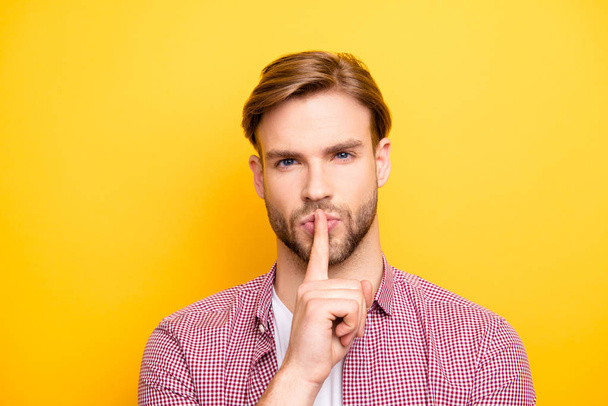 Close up portrait of confident pensive dreamy handsome sexy guy with stylish modern hairdo holding forefinger near mouth asking to be quiet isolated on bright yellow background copy-space - Фото, изображение