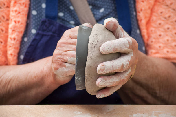 closeup of hands of old woman making clay pottery bowl in outdoor  - Фото, зображення