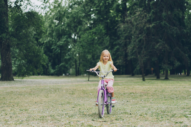 улыбающийся ребенок катается на велосипеде в летнем парке
 - Фото, изображение