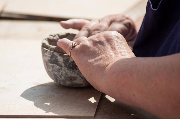 closeup of hands of old woman making clay pottery bowl in outdoor  - Foto, Bild