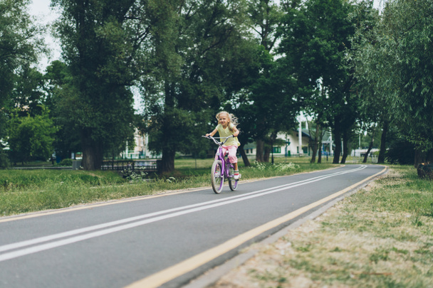 μικρό παιδί ιππασία ποδήλατο στον δρόμο, στο πάρκο θερινή ημέρα - Φωτογραφία, εικόνα