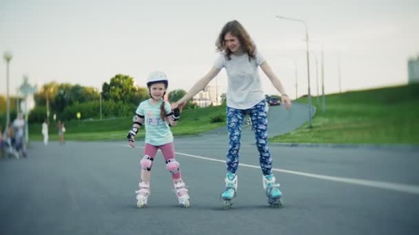Mother helps her daughter to skate in a roller-skating park - Záběry, video