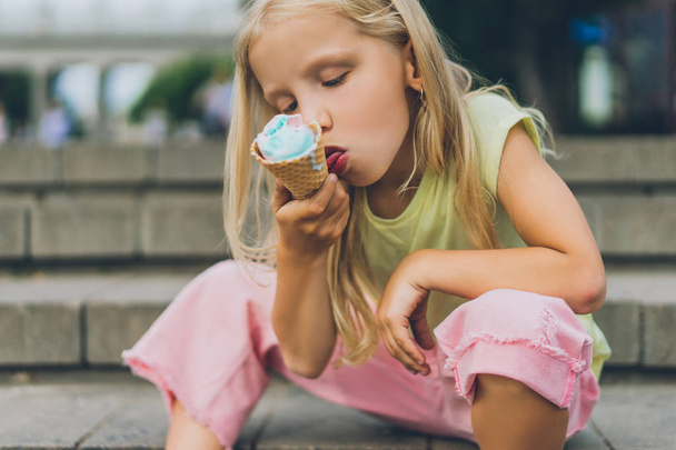 selective focus of cute child with ice cream sitting on city steps alone - Fotó, kép