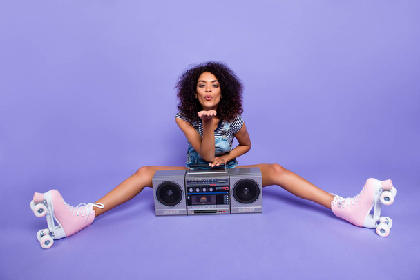 Portrait of lovely flirting girl wearing roller skates having boom box blowing air kiss with pout lips palm at camera isolated on vivid violent background retro vintage quad student concept - Foto, imagen