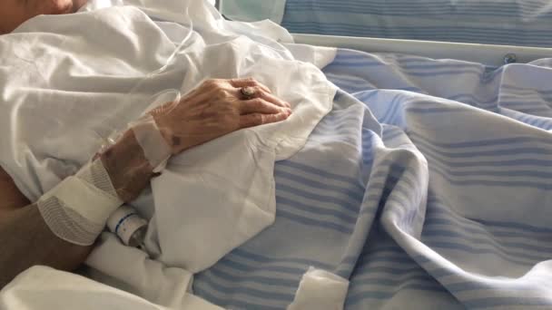 Hand van een oudere patiënt op een medische bed in ziekenhuis kamer slapen  - Video