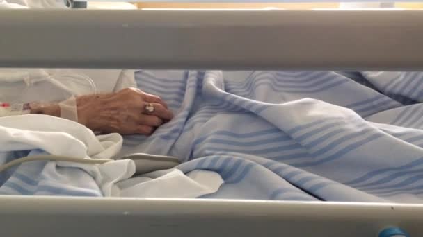 Hand eines älteren Patienten, der auf einem Krankenhausbett schläft  - Filmmaterial, Video