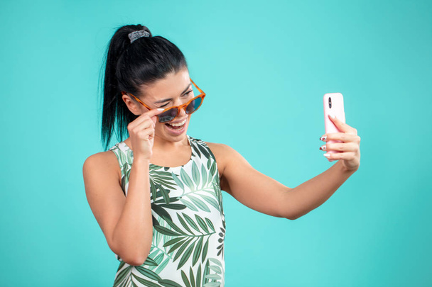 joyful brunette girl winking to the camera of her smartphone - Foto, Imagen