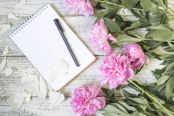 Abra o bloco de notas em branco, caneta e peônia na mesa de madeira branca. romântico flat lay
 - Foto, Imagem