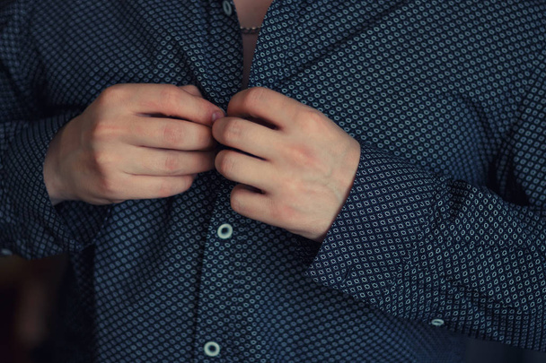 Man buttoning blue shirt. - Фото, изображение