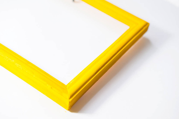 жовта дерев'яна фоторамка, пофарбована гуашною фарбою груба текстура, знаходиться поруч у банці з пензлем на білому тлі
 - Фото, зображення