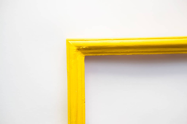 yellow wooden photo frame painted with gouache paint rough texture is next in a jar with a brush on a white background - Photo, image