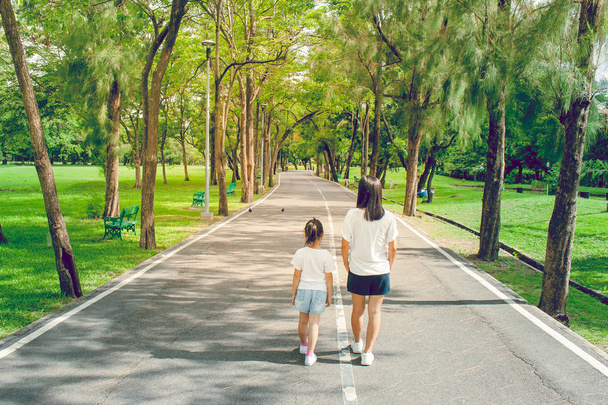 Женщина и ребенок идут по тропинке и тропинке в общественном парке, чувствуют себя счастливыми и наслаждаются
. - Фото, изображение