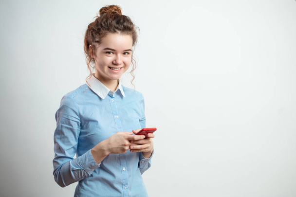 close up portrait of cheerful female student in casual outfit holding mobilwe phone - Foto, Imagen