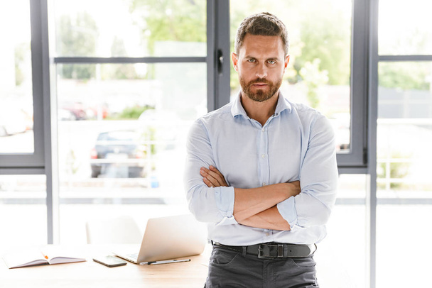 Image of handsome bearded man in office standing near table working looking camera. - Fotografie, Obrázek