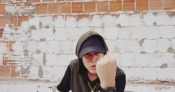 Mladý muž taneční hip-hop na ulici před cihlová zeď - Záběry, video