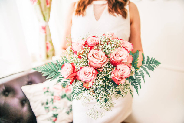 Nieuw wo vrouw houdt haar bruids boeket met trouwringen op een roos - Foto, afbeelding