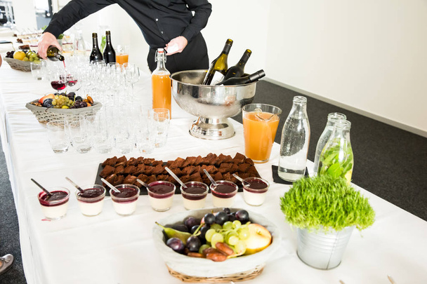 Catering-Desserts auf Buffet-Tisch mit Mann serviert Wein im Hintergrund - Foto, Bild