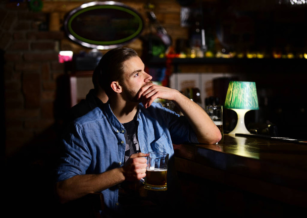 Guy sitting at bar counter and drinks beer. - Foto, imagen