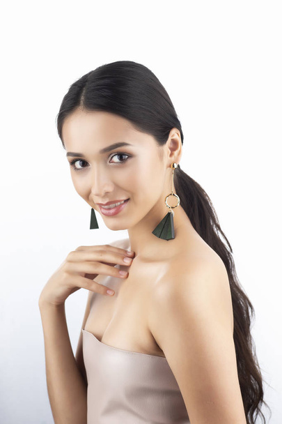 Beauty portrait of a beautiful smiling brunette girl model with bare shoulders and brown eyes wearing earrings imitation jewelry isolated on white background. Commercial design. Copy space. - Foto, afbeelding